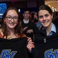 Two girls hold up a GV Alumni t-shirt that they caught.